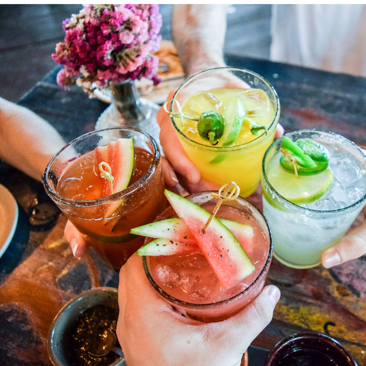 4 colorful drinks held by hands
