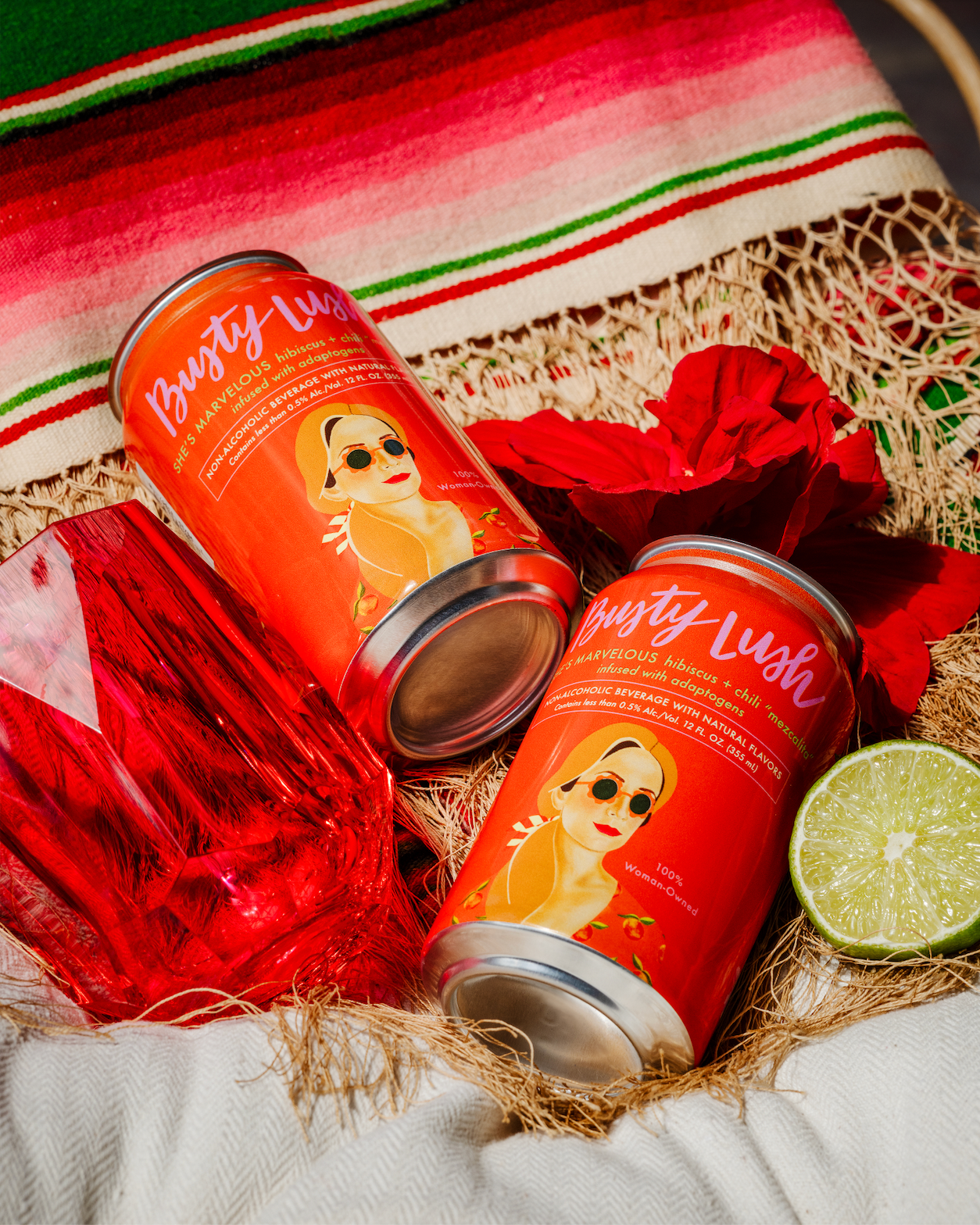 Two red cans with colorful labels on a festive background with a lime and red fabric.